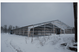 Arbetarna trotsar snöstormen och monterar detaljer på ridhuset.